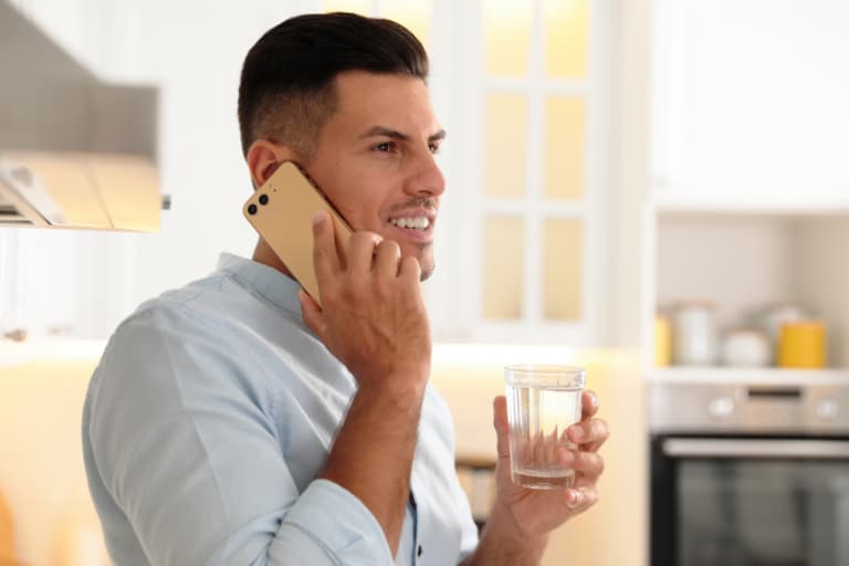 man with glass of water talking on phone